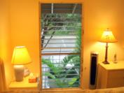 A102 - Back bedroom window looking out toward parking, office, tennis court, pool and BBQ with Haleakala Crater in background.